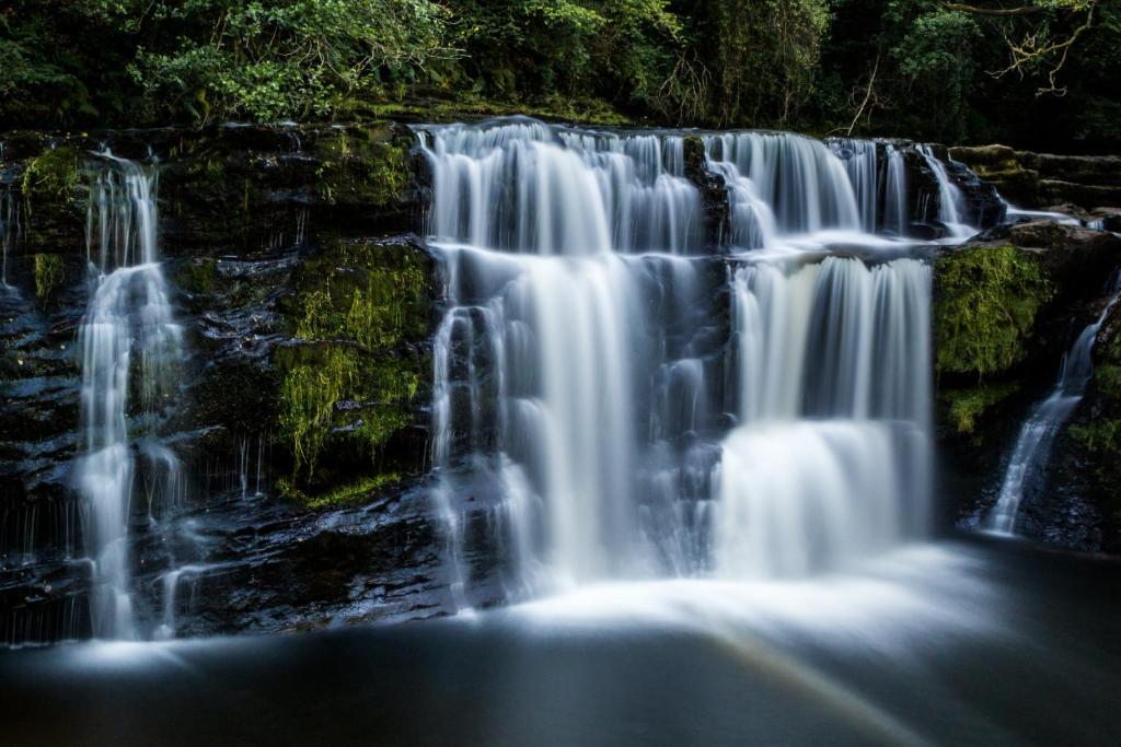 a waterfall in the middle of a forest at K Suites - Robert Street in Trehafod