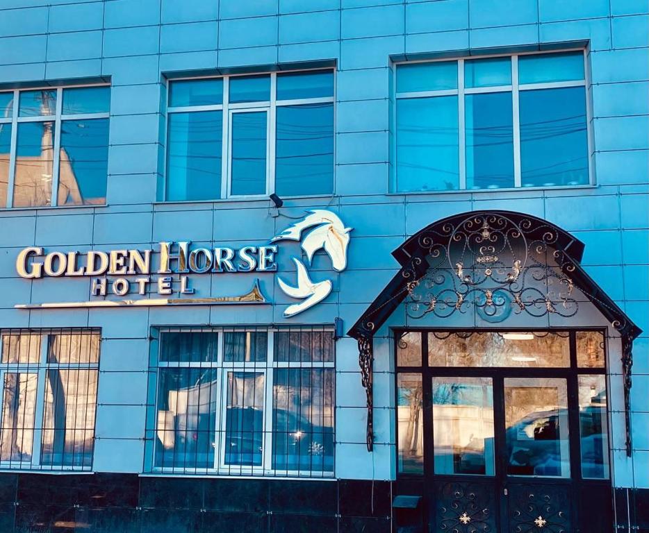 um edifício azul com um sinal para um hotel de cavalos dourados em Golden Horse Hotel em Taldykorgan
