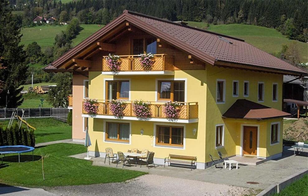 a yellow house with a balcony and a table at Hallerhaus in Altenmarkt im Pongau