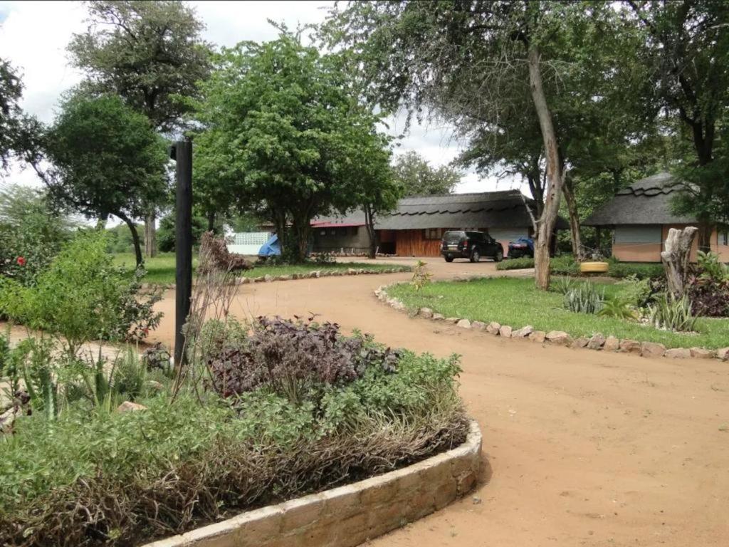 a dirt road in front of a house with trees at Hippo Paradise Lodge and Campsites in Kariba