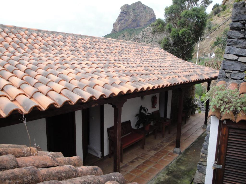 Casa blanca con techo de baldosa y banco en Casa Rural Guaidil, en Vallehermoso