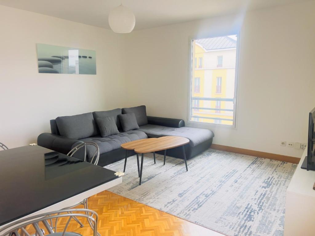 een woonkamer met een bank en een tafel bij EXIGEHOME - Grand T4 en centre ville à 10 min du RER A in Maisons-Laffitte