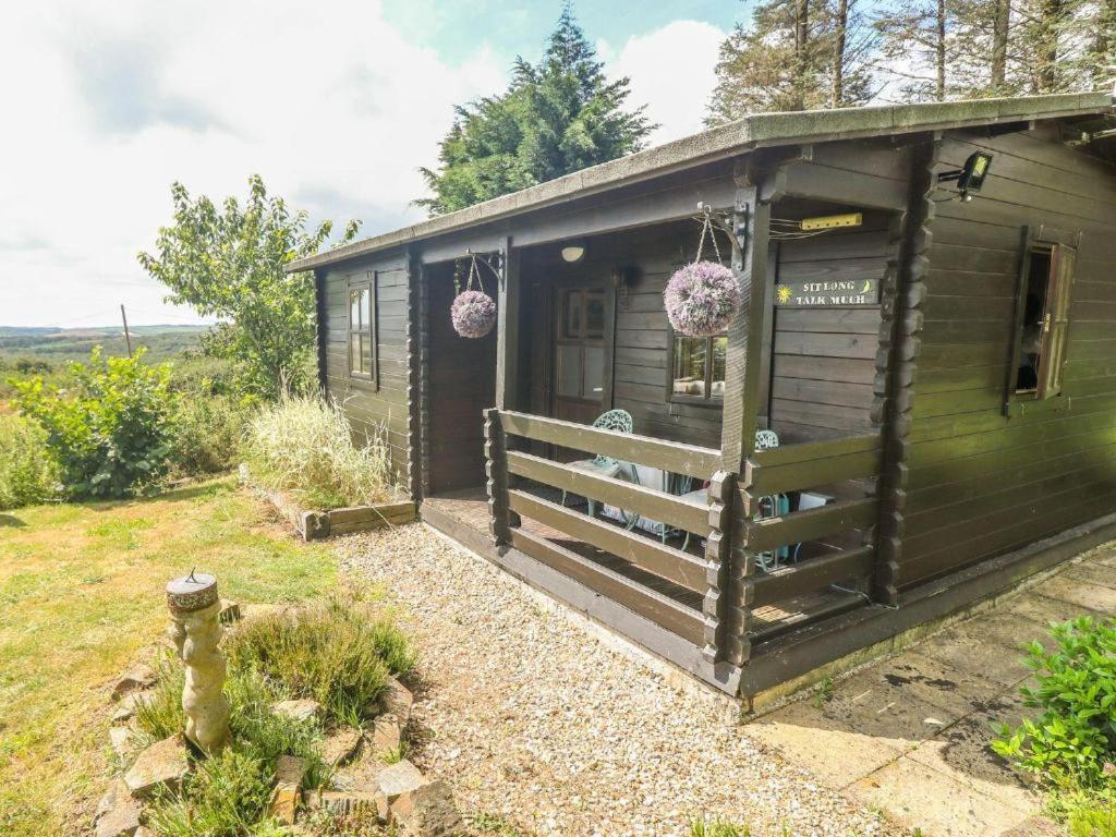 een groene hut met een veranda en een deur bij Trevenna Cabin in St Austell