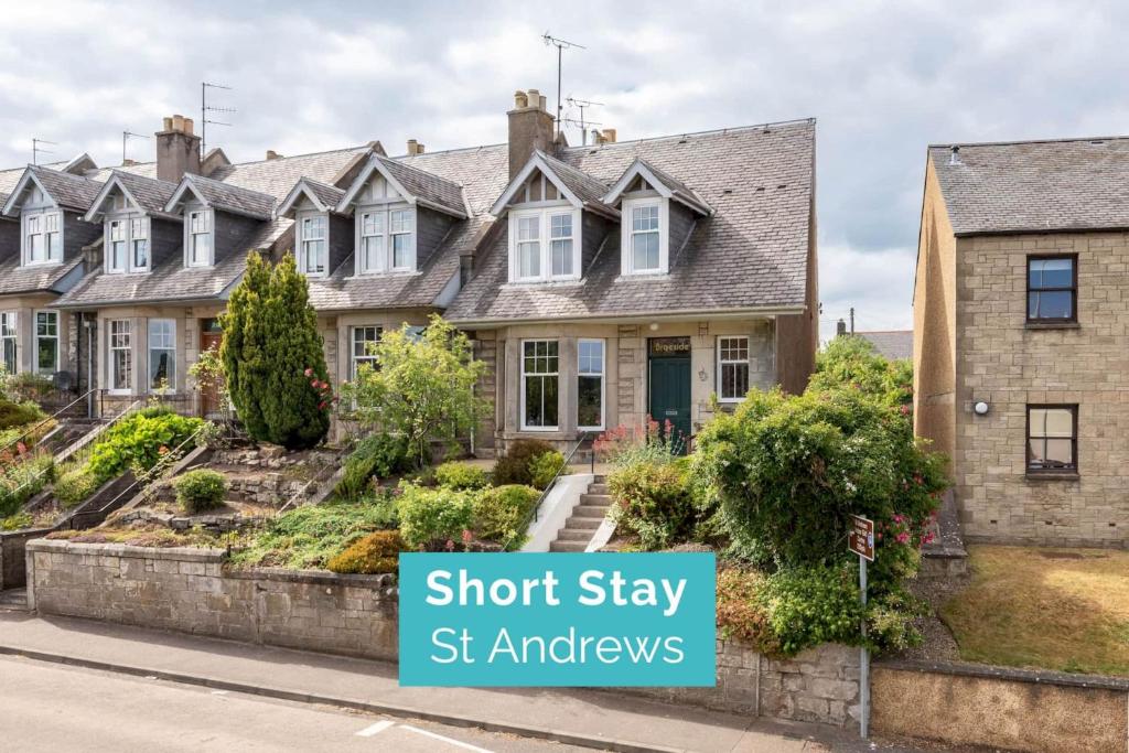 uma fila de casas com um cartaz que diz estadia curta St amances em Braeside - 4 Beds - Sleeps 8 - Garden em St. Andrews