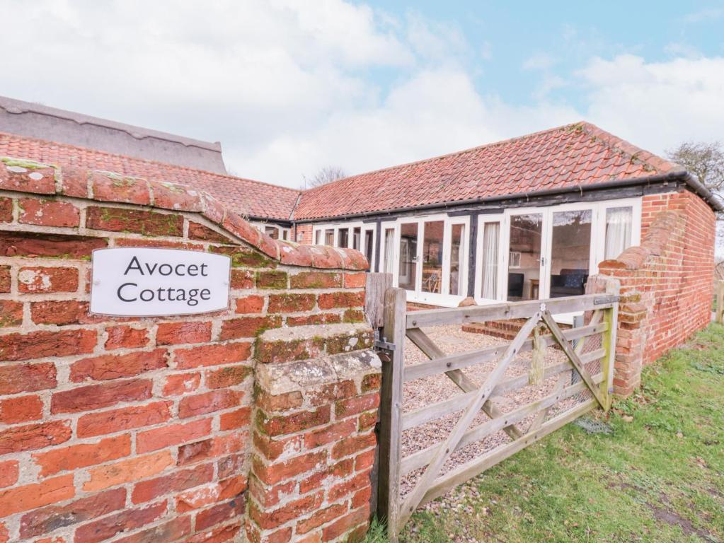 a brick building with a sign that reads inspect cottage at Avocet Cottage in Saxmundham