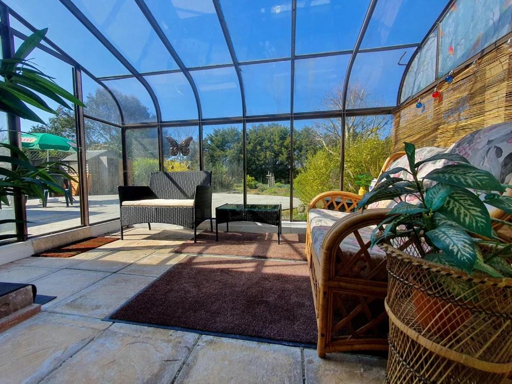 a glassconservatory with chairs and a table and a plant at Sea Shells in Greatstone