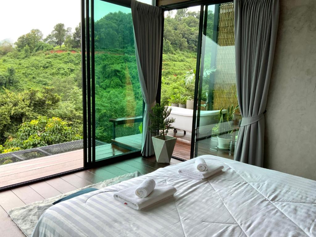 a bedroom with a bed and a large window at Camp Mai Mee Chue in Pong Yaeng