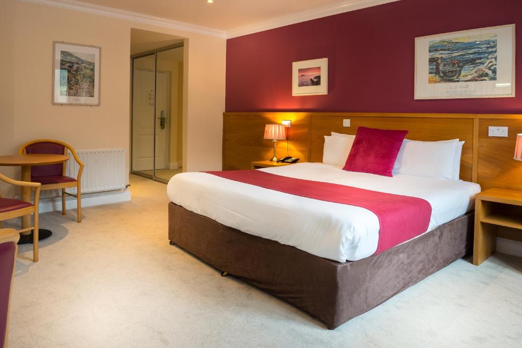 a hotel room with a large bed with red walls at Hotel Ceann Sibeal in Dingle