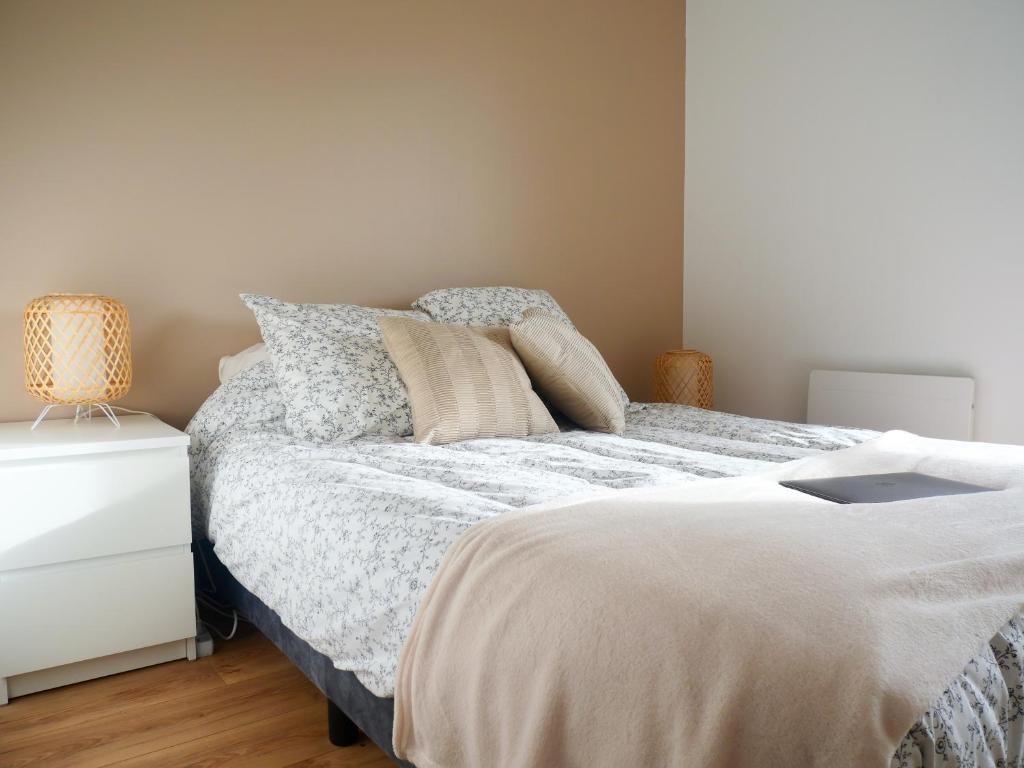 1 dormitorio con cama con almohadas y mesita de noche en Joli appartement à Lannion, en Lannion