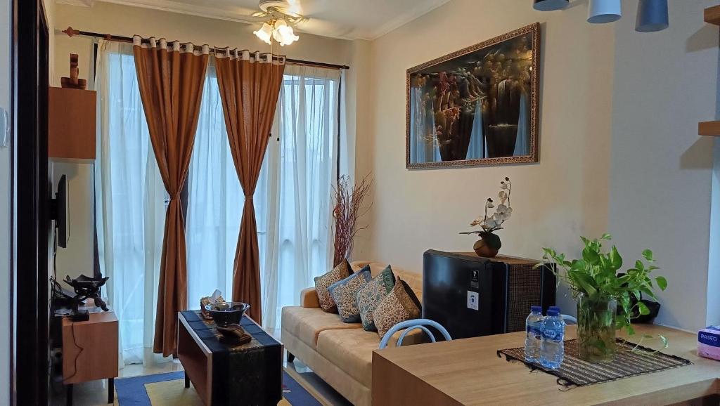 a living room with a couch and a table at Cozy Apartment Asatti Agate Yellow Vanya Park in Pagedangan