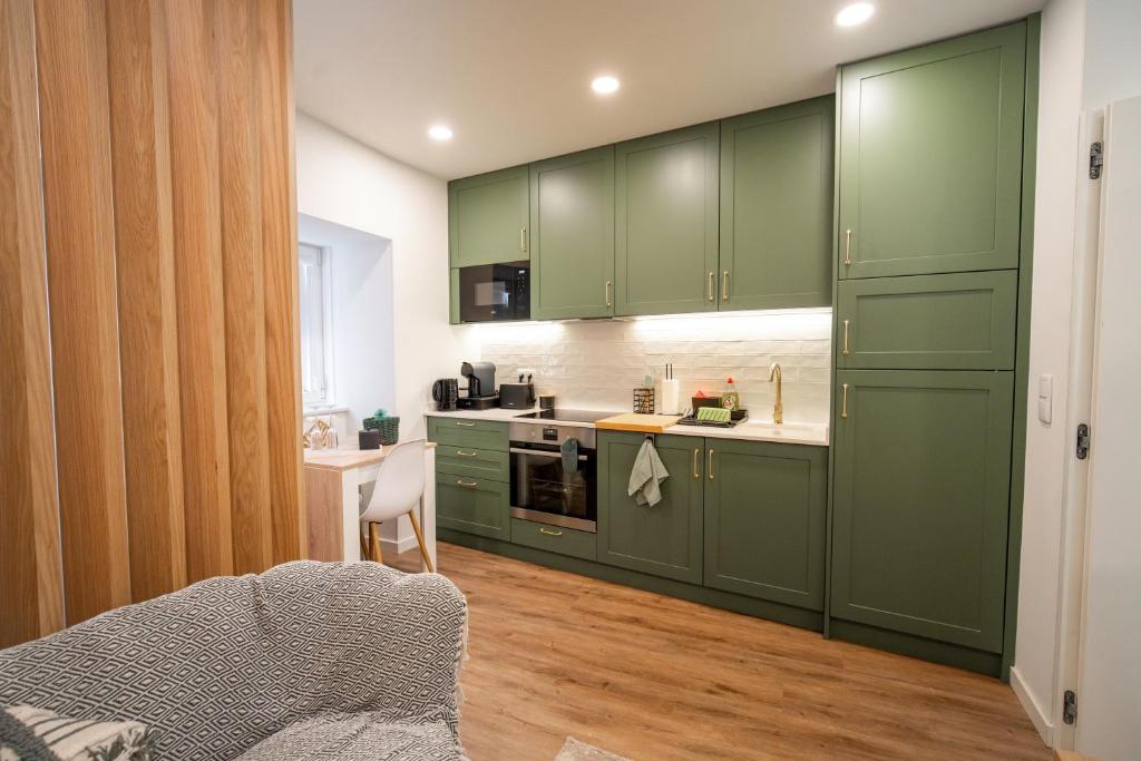a kitchen with green cabinets and a table at MAM HEAT River Nest - Darque Village Centre in Viana do Castelo