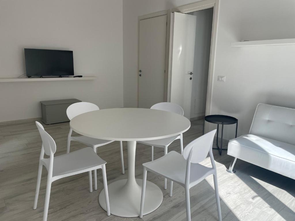 a white table and chairs in a room with a tv at ucuppu appartamenti Civico16 in Carloforte
