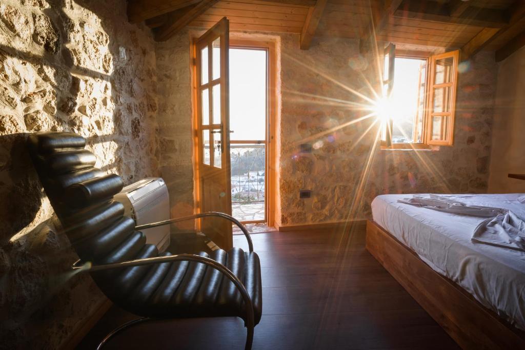 a room with a chair and a bed and a window at Roots Dhermi in Dhërmi