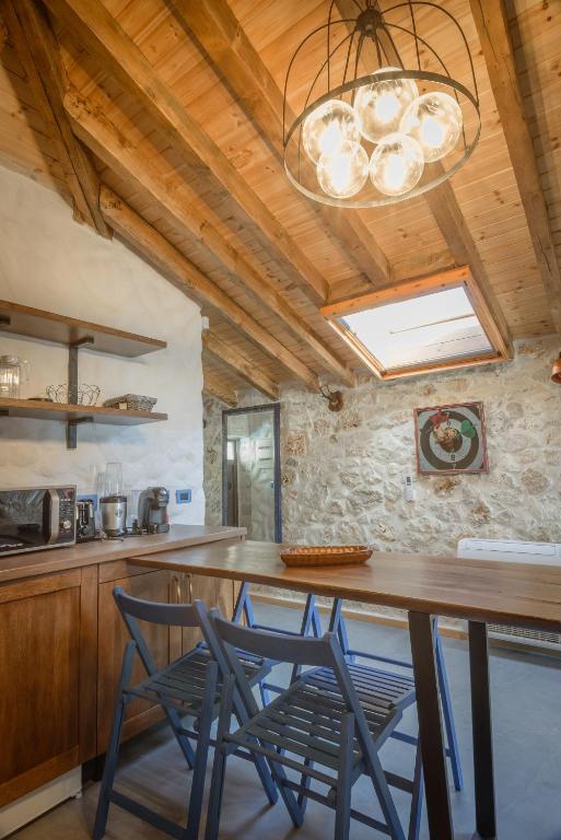 a kitchen with a wooden ceiling with a chandelier at Roots Dhermi in Dhërmi