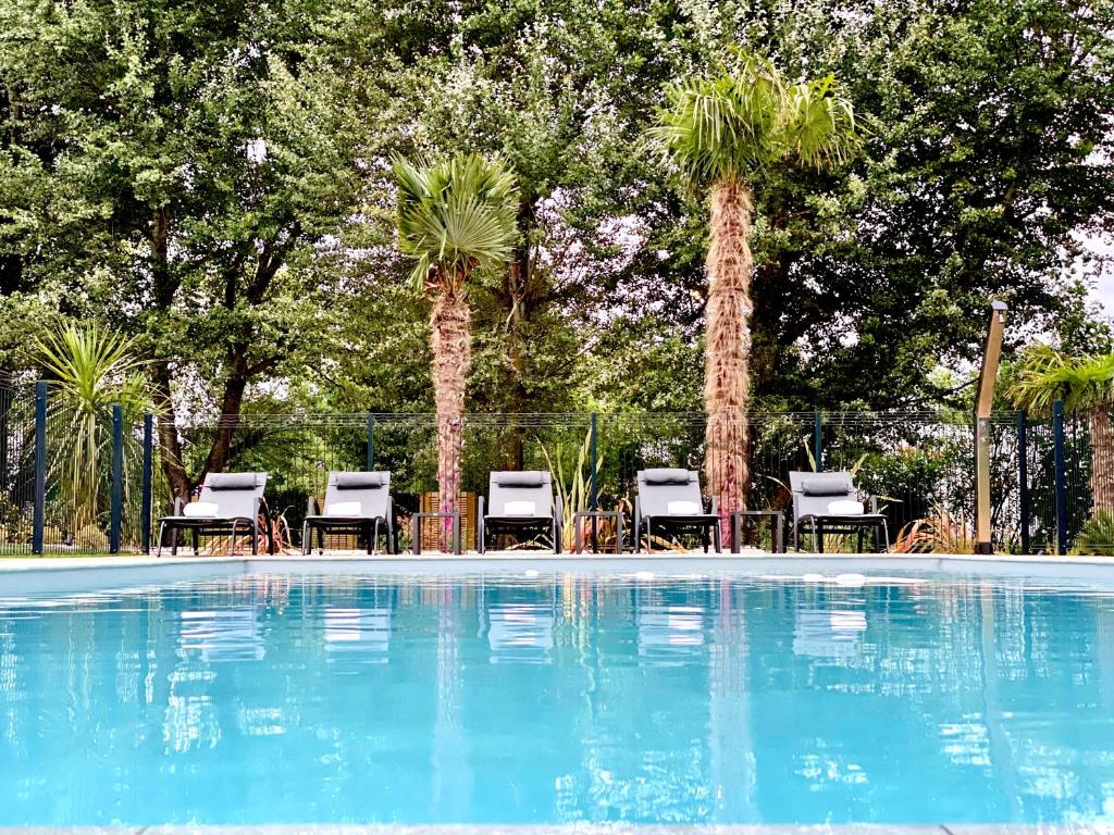 a swimming pool with chairs and palm trees at Hotel Restaurant Du Parc Saumur Logis Elégance in Saumur