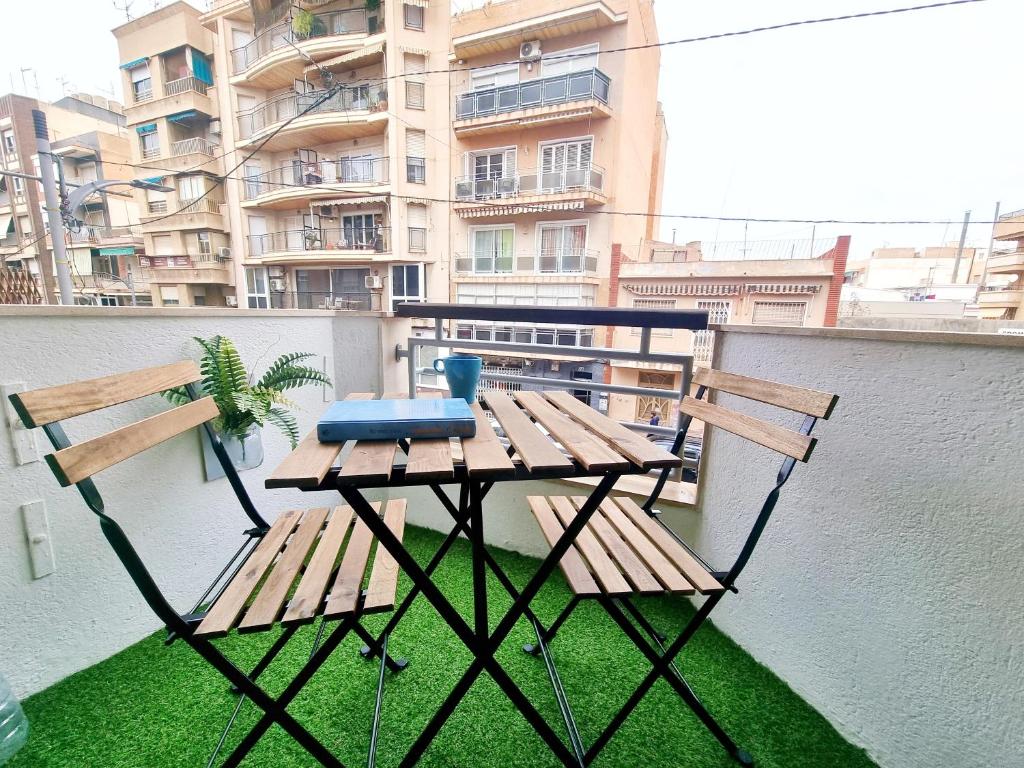 einen Tisch und zwei Bänke auf einem Balkon mit einem Gebäude in der Unterkunft Avenida Principal con Wifi y Smart Tv - By Aloha Palma in Águilas