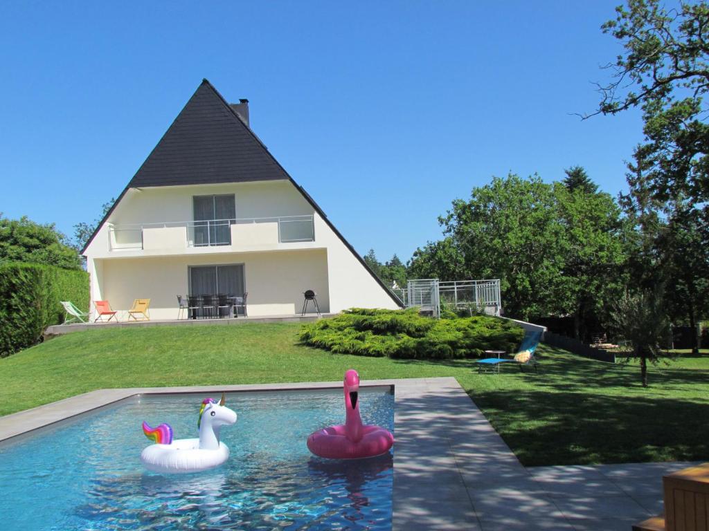 two pink swans in a swimming pool in front of a house at Maison d'hôtes kerwall in Malville