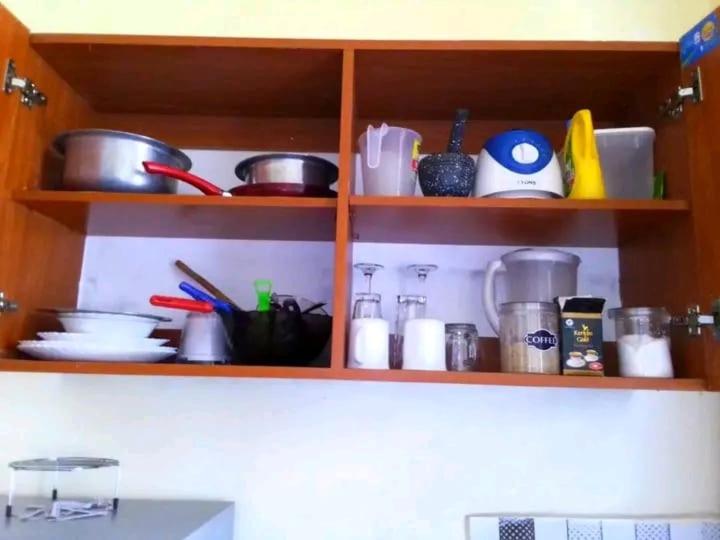 a kitchen shelf filled with pots and pans and utensils at Leo's Enchanting homes in Mombasa
