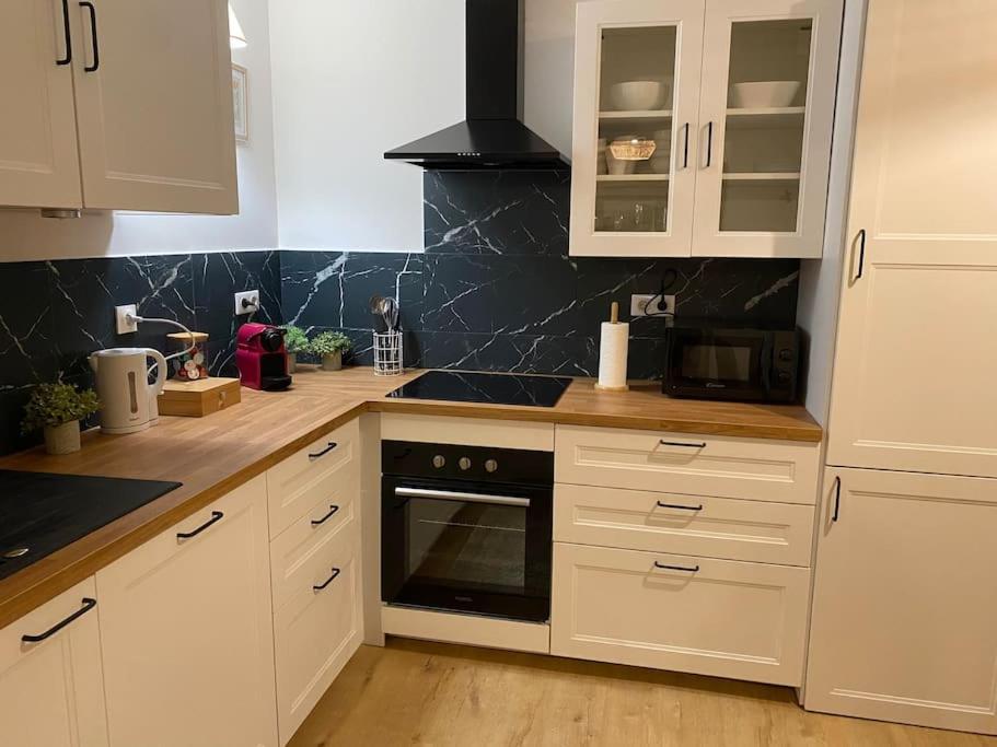 a kitchen with white cabinets and a stove top oven at Charmant T3 à côté des Thermes in Luxeuil-les-Bains