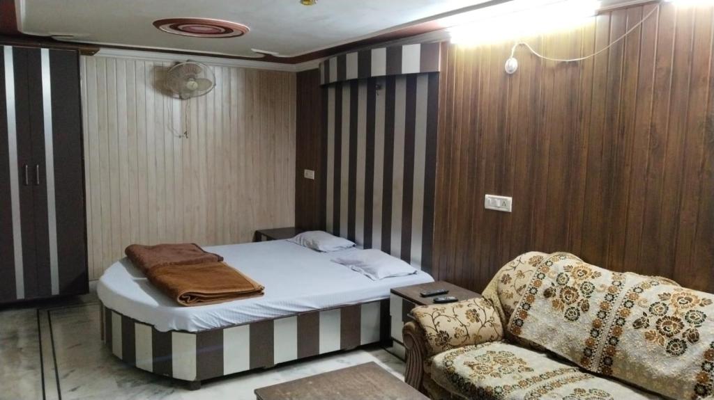 Hotel plaza في Rohtak: غرفة نوم صغيرة مع سرير وأريكة