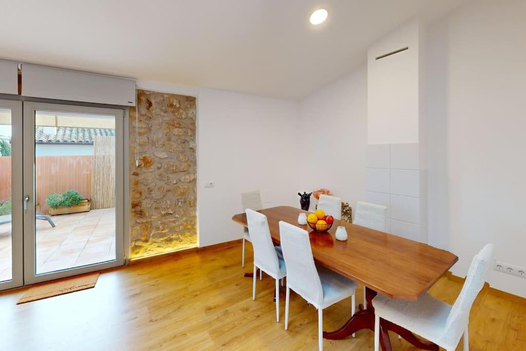 ein Esszimmer mit einem Holztisch und weißen Stühlen in der Unterkunft Can Xec - casa reformada Pals in Pals