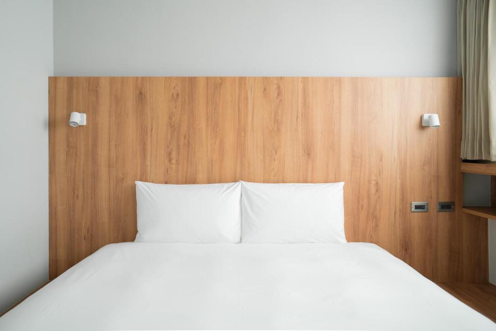 1 cama con almohadas blancas y cabecero de madera en Norden Ruder Hostel Taitung Branch 2 en Taitung