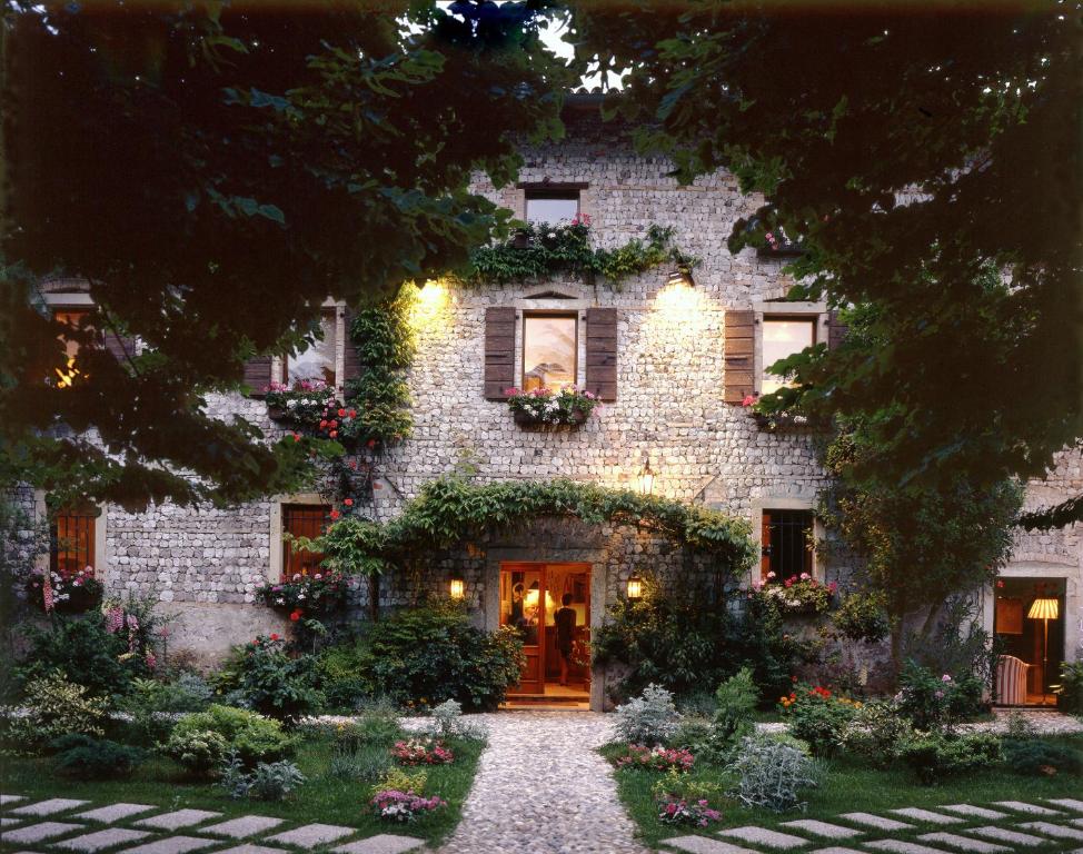 un vieux bâtiment en pierre avec des fleurs devant lui dans l'établissement Hotel L'Ultimo Mulino, à Bannia