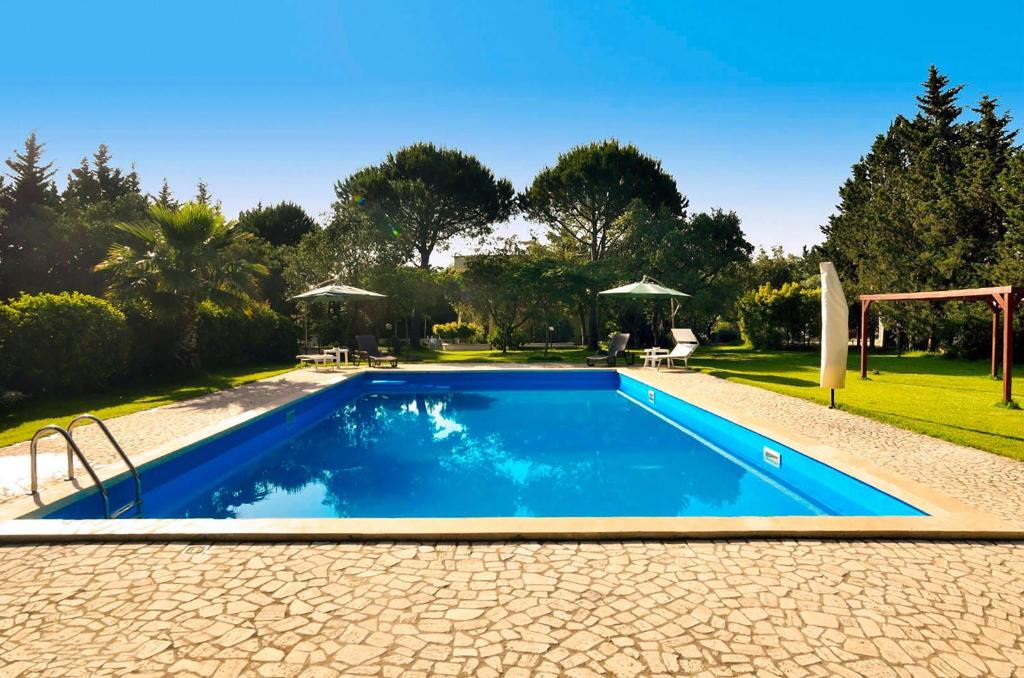 a swimming pool in a yard with a table and chairs at Tenuta Primaterra in Melendugno