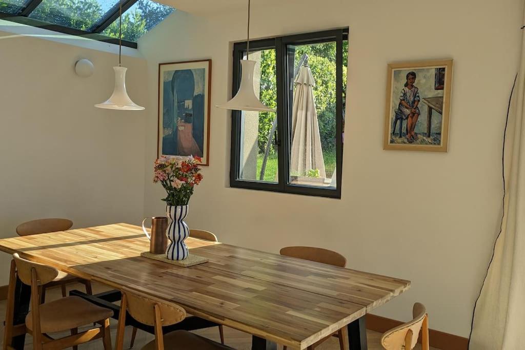 Villa Brunelle, Vue bords de Rance في Le Minihic-sur-Rance: غرفة طعام مع طاولة وكراسي خشبية