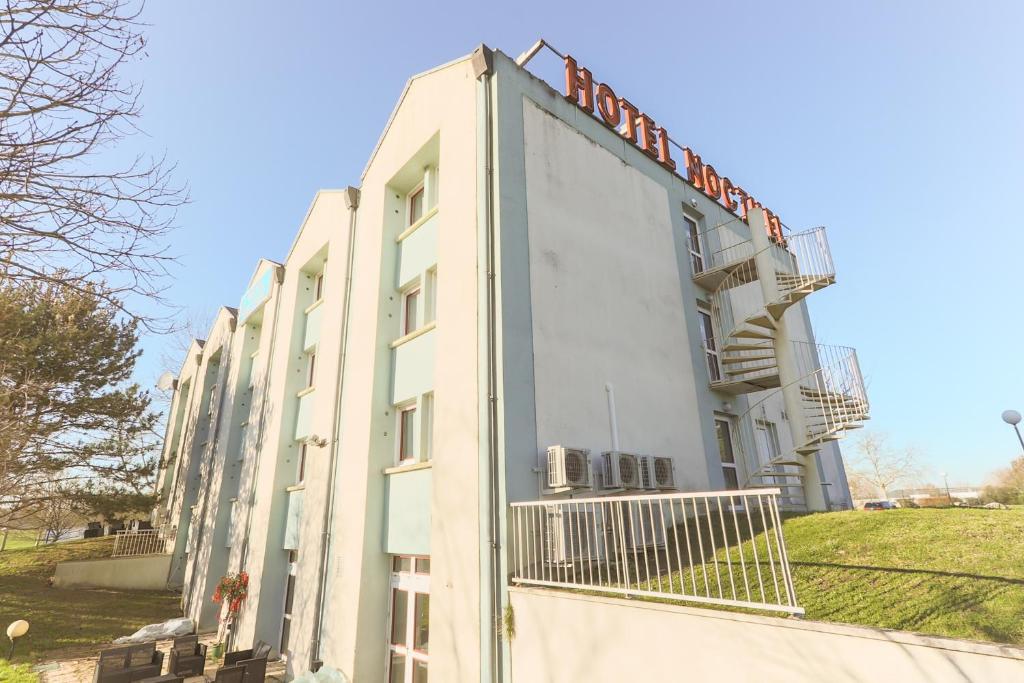 a white building with a sign on the side of it at HOTEL NOCTUEL in Rambouillet