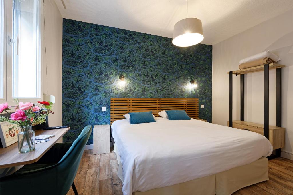 um quarto com uma grande cama branca, uma secretária e uma mesa com cadeiras em Contact Hôtel du Commerce et son restaurant Côte à Côte em Autun