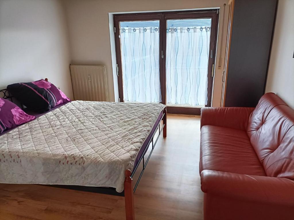 ein Schlafzimmer mit einem Bett, einem Sofa und einem Fenster in der Unterkunft Apartment Bamboleo in Veringendorf