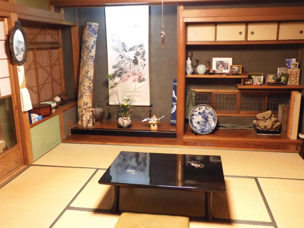 salon ze stołem i półkami w obiekcie Japanese Traditional House with beautiful garden. w mieście Fujisaka