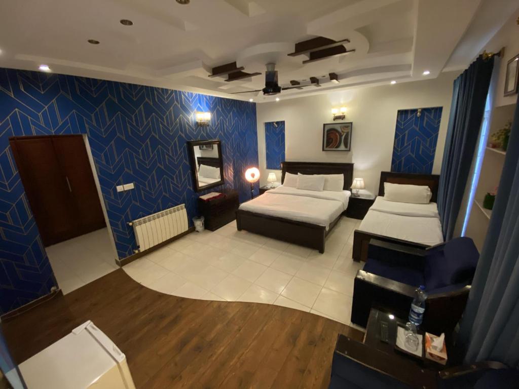 a bedroom with two beds and a blue wall at Harvey's Islamabad in Islamabad