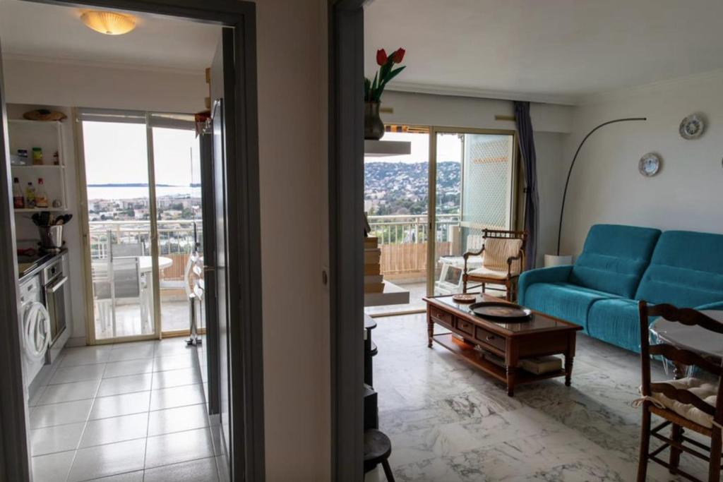 un salon avec un canapé bleu et un balcon dans l'établissement Lovely 48 m2 appt with sea view and swimming pool, à Antibes