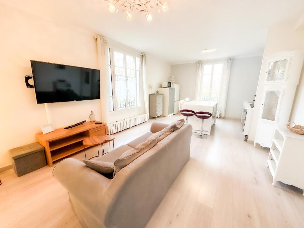 a living room with a couch and a flat screen tv at Bel appartement à 10 minutes de Disney in Quincy-Voisins