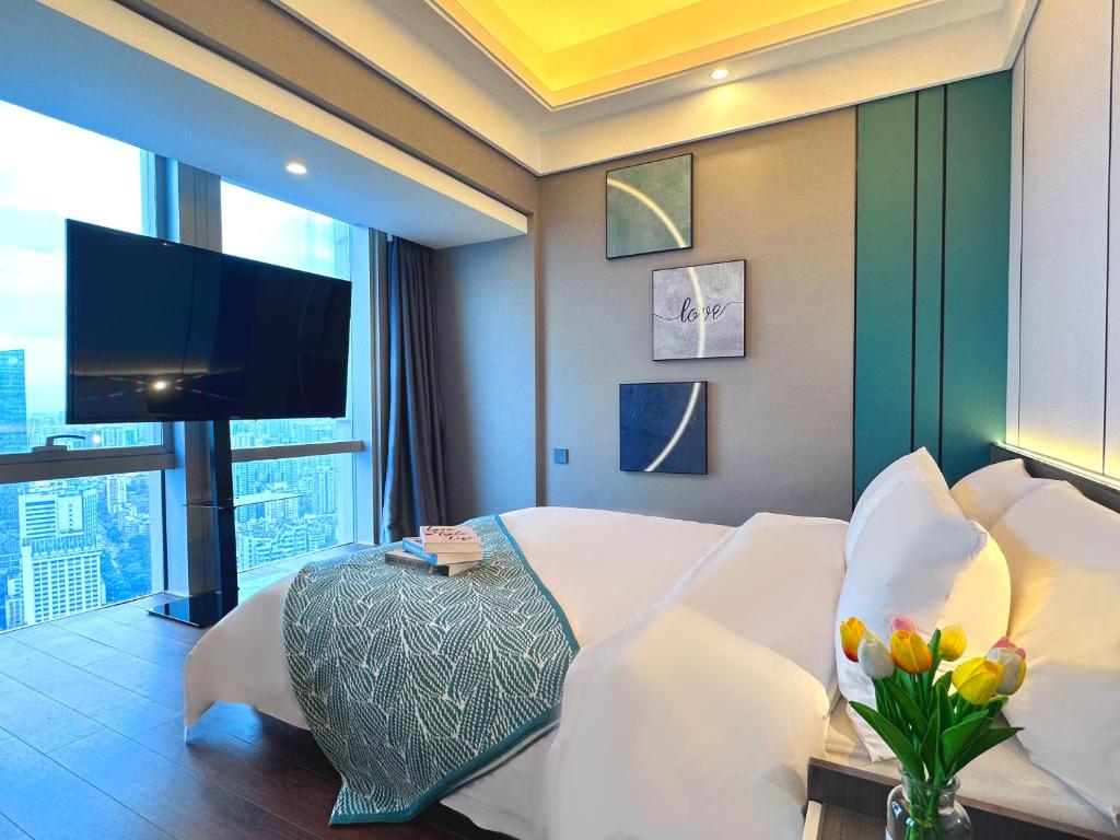 a hotel room with a bed and a flat screen tv at Guangzhou Xing Yi International Apartment Hotel - Vertical City Branch in Guangzhou