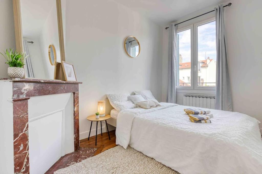 a white bedroom with a bed and a fireplace at Appartement chic proche gare de Clamart + Netflix in Malakoff