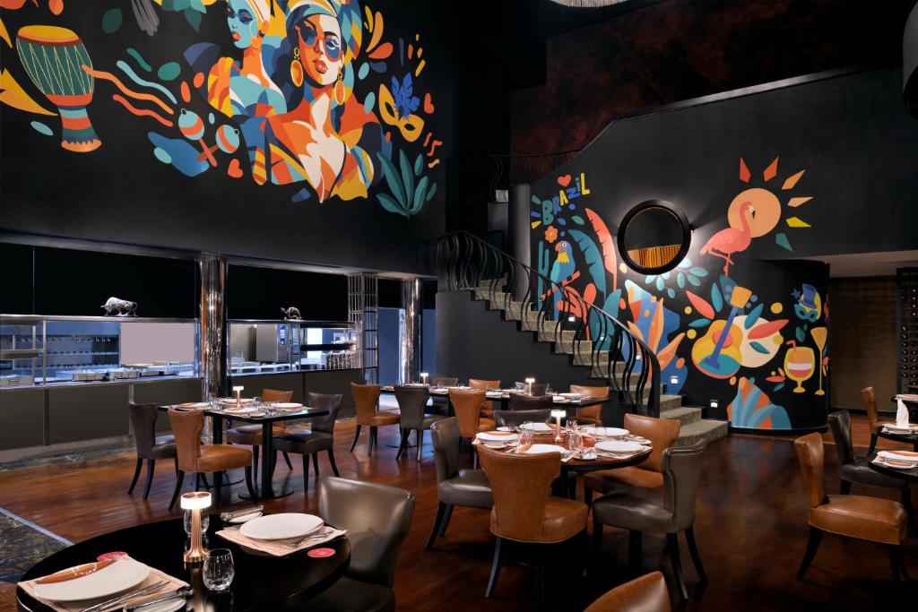 a restaurant with tables and chairs and a colorful wall at InterContinental Abu Dhabi by IHG in Abu Dhabi