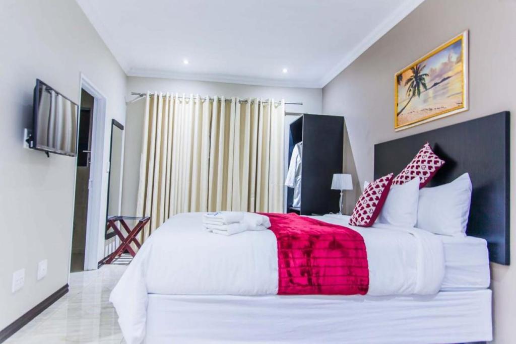 a bedroom with a large white bed with red and white pillows at Heavenly Boutique Hotel in Johannesburg