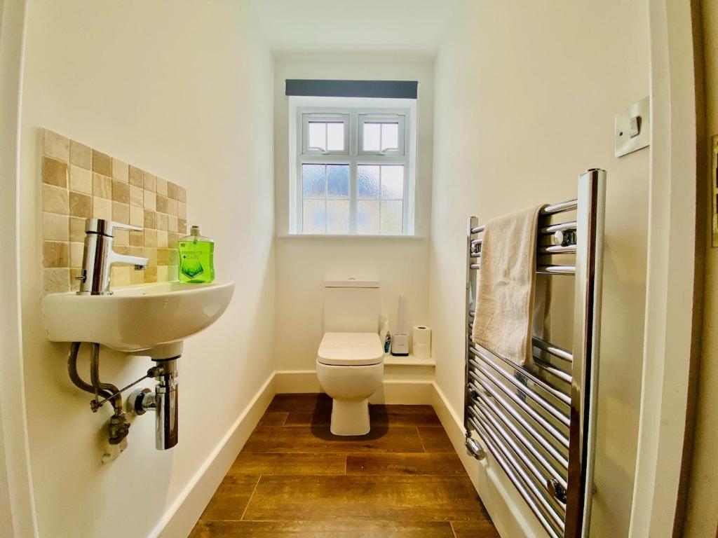a bathroom with a toilet and a sink and a window at Just £45pppn! Prime Comfort for Contractors with Spacious Parking, Plush Beds, Top-notch Amenities, Flexible Stays & Lightning-Fast Internet in Woking