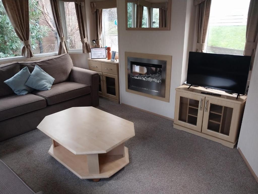 a living room with a couch and a tv and a coffee table at A Hillside Retreat - with garden in Hastings