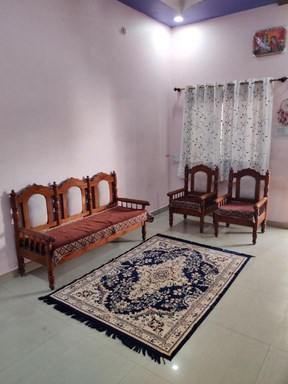 a room with two beds and two chairs and a rug at Madhuban Homestay 1 Ujjain in Ujjain