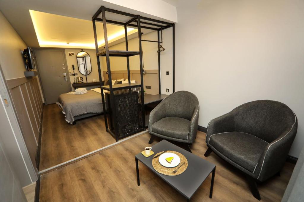 イスタンブールにあるArkem Hotel 2の椅子2脚、ベッド1台、鏡が備わる客室です。