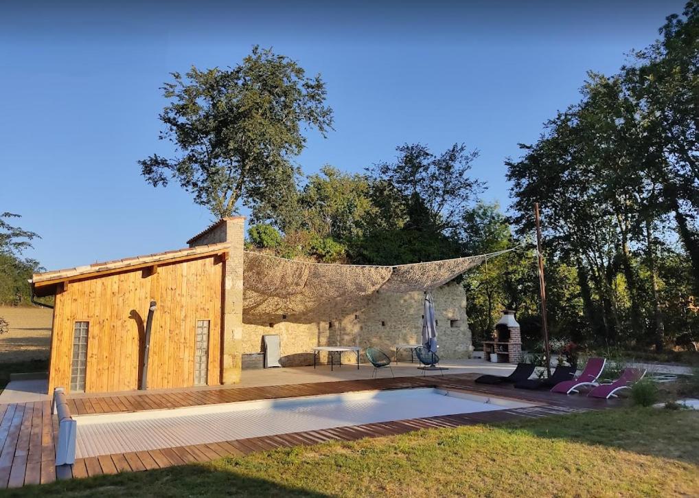 une maison avec une piscine en face d'un bâtiment dans l'établissement Gîte campagne famille 15 pers Piscine chauffée Jeux enfants Pétanque, à Saint-Sauvy