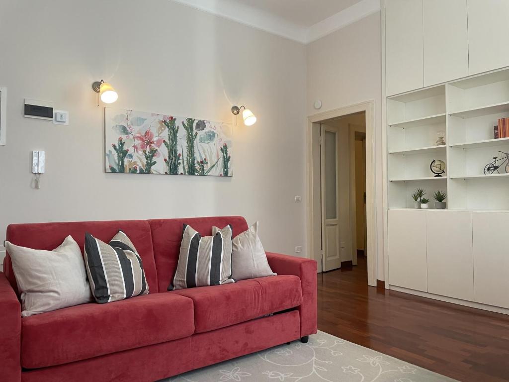 un divano rosso con cuscini in soggiorno di Umbria 60 Apartment a Milano