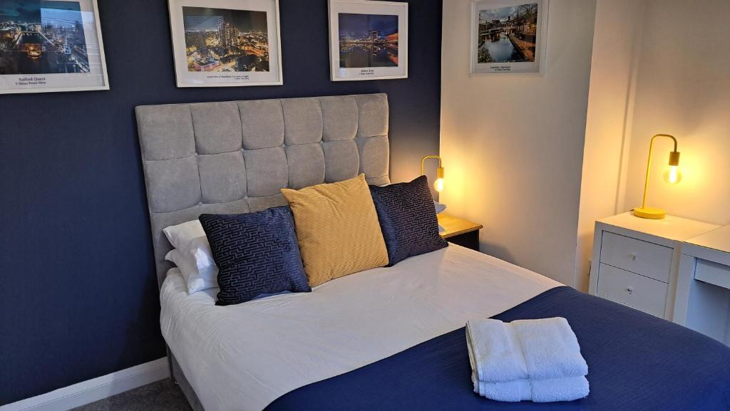 a bedroom with a large bed with blue and yellow pillows at The Heart - Cosy 3 bedroom house with double driveway and Garden in Manchester in Manchester