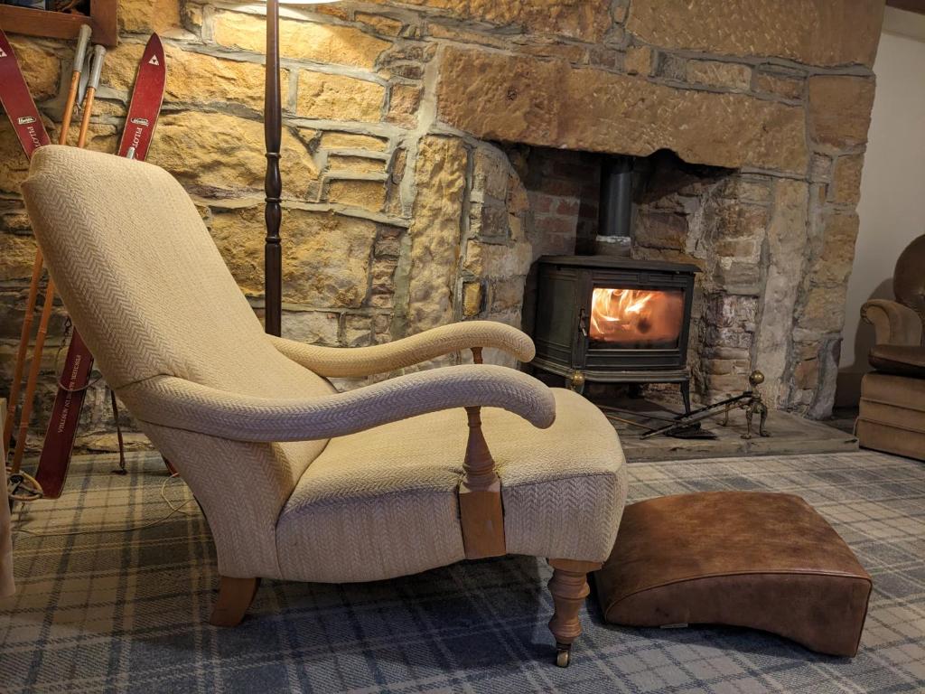 a living room with a chair and a fireplace at Historic character cottage in central Dornoch in Dornoch