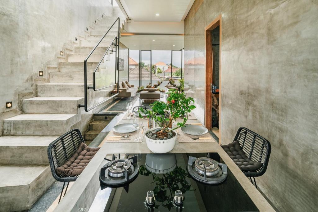 een eetkamer met een tafel en stoelen en een trap bij Casa Jenah Three Bedroom Villa in Kesiman