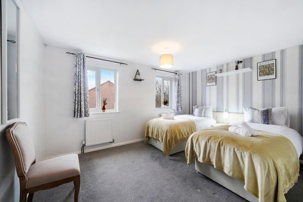 a bedroom with two beds and a chair at Beautiful 2 Bedroom house, Wendover Free Parking in Wendover